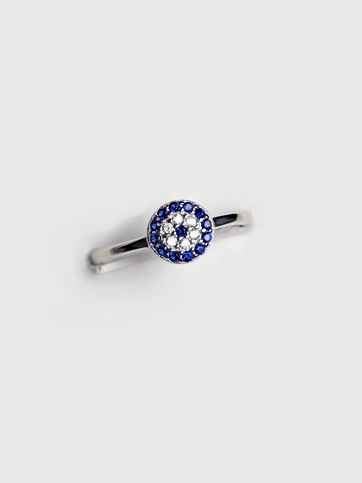 Silver ring with blue and clear gemstones on a light gray background