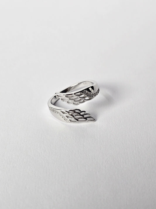 Silver wing-shaped ring on a light gray background