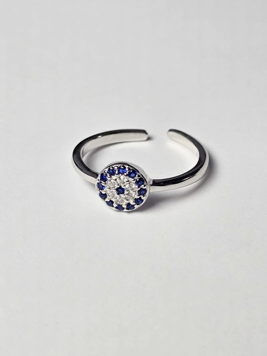 Silver evil eye ring with blue and white gemstones on a light grey background