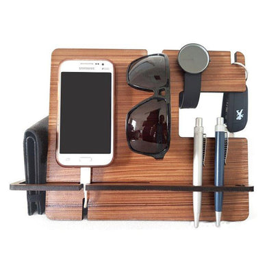 Wooden men's docking station displaying a charging phone, wallet, watch, pens, keys and sunglasses.