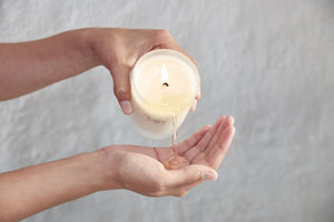 Pouring warm soy candle wax on skin for massage.