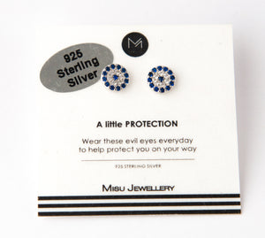 A set of sterling silver studs in style of the evil eye with blue cubic zirconia stones encircling white stones and a single blue stone in the middle